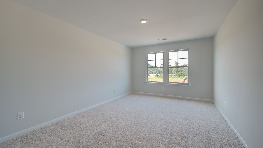 Secondary bedroom with neutral walls, carpet flooring, and natural light in the Clarity at Brighton in Locust Grove, GA.