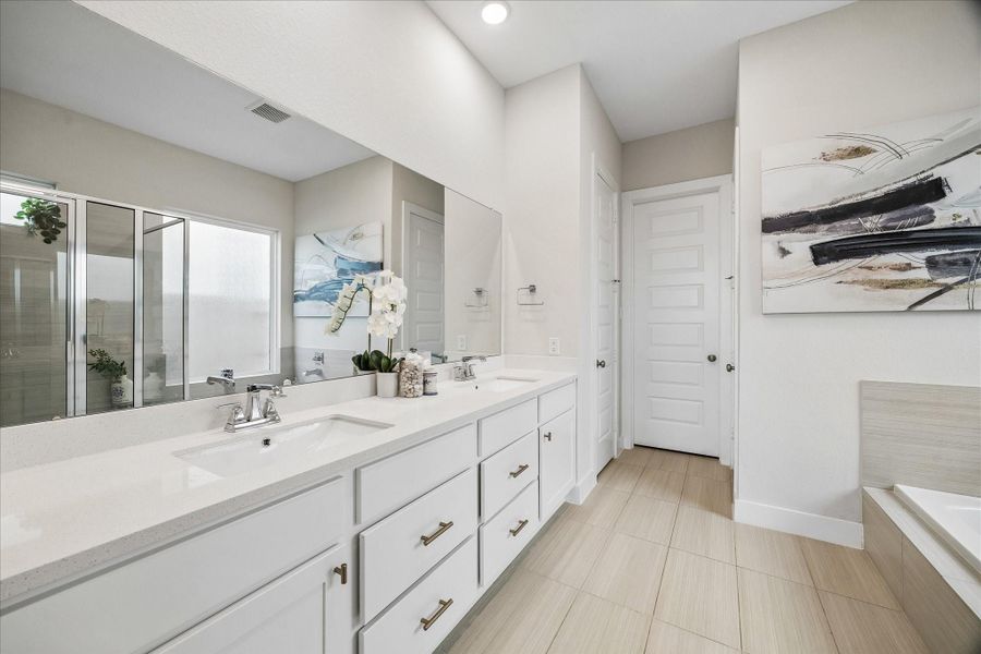 A spacious double vanity provides ample counter space and storage, with convenient access to the linen closet and the expansive primary walk-in closet.