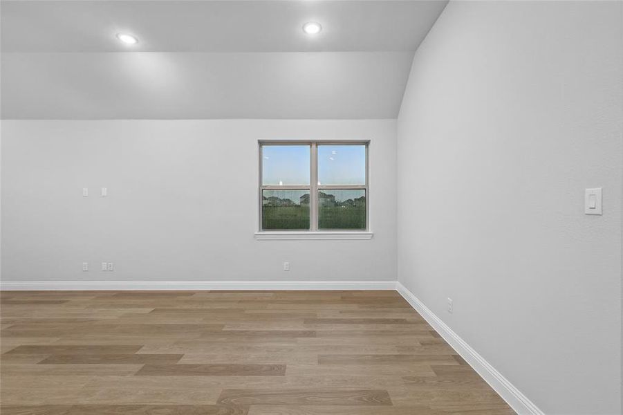 Empty room with vaulted ceiling, light wood-type flooring, and recessed lighting Empty room with vaulted ceiling, light wood-type flooring, and recessed lighting