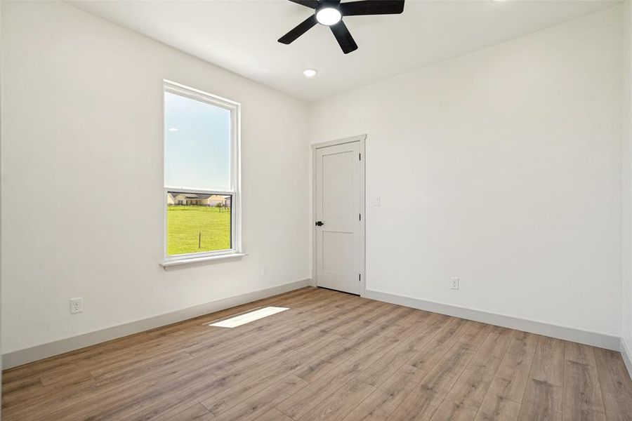 Bedroom 3 featuring wood-finish flooring, white walls, and a single window with a white frame
