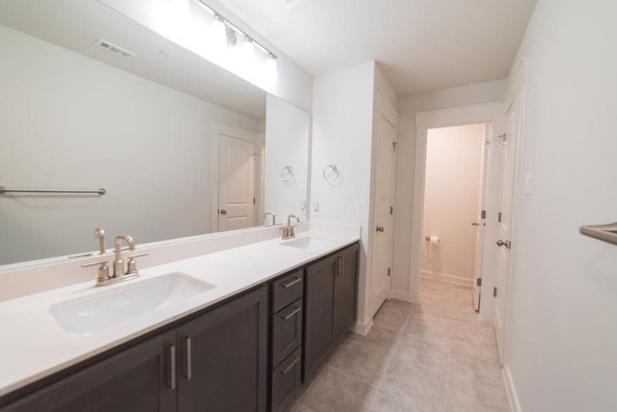 Full bathroom with double vanity and light tile patterned floors
