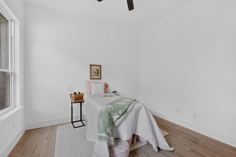 Interior room featuring light wood-finish flooring, white walls, and a ceiling fan