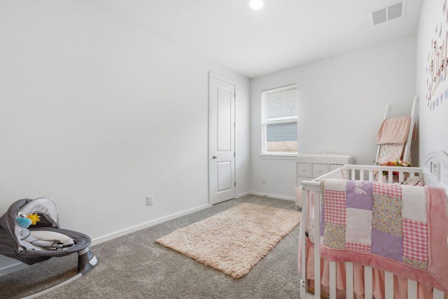 Bedroom featuring light carpet and a crib