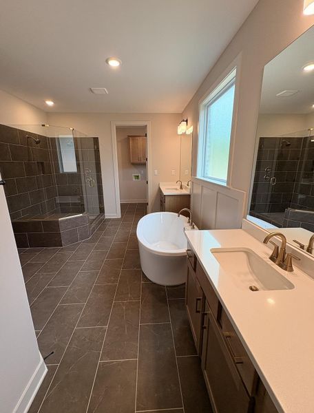 Spacious bathroom featuring an oval freestanding soaking tub and an expansive walk-in shower with tile surround and glass enclosure
