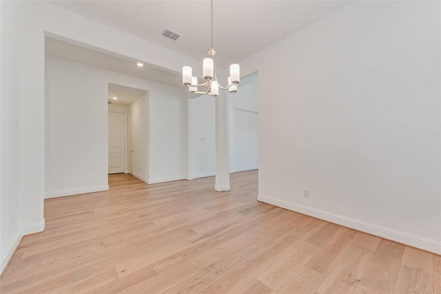 Unfurnished dining area featuring light hardwood / wood-style floors and a notable chandelier