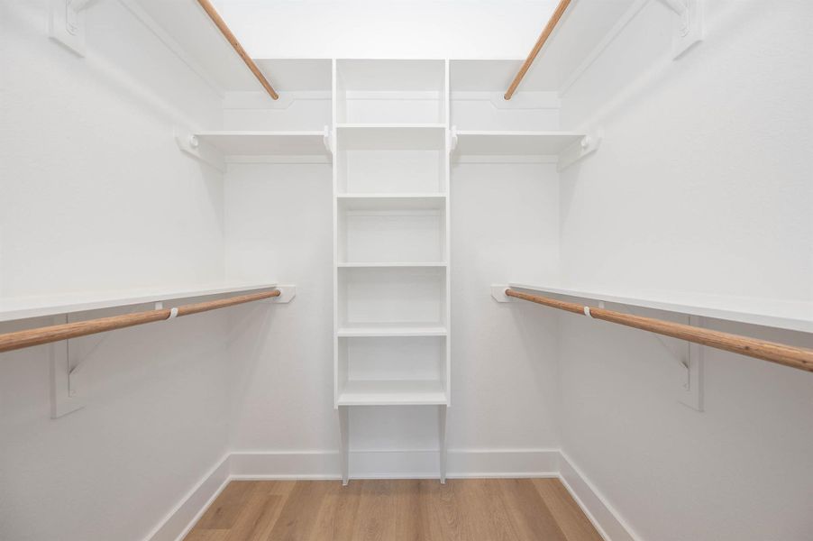 Spacious walk-in closet featuring built-in shelving and dual hanging rods for effortless organization.