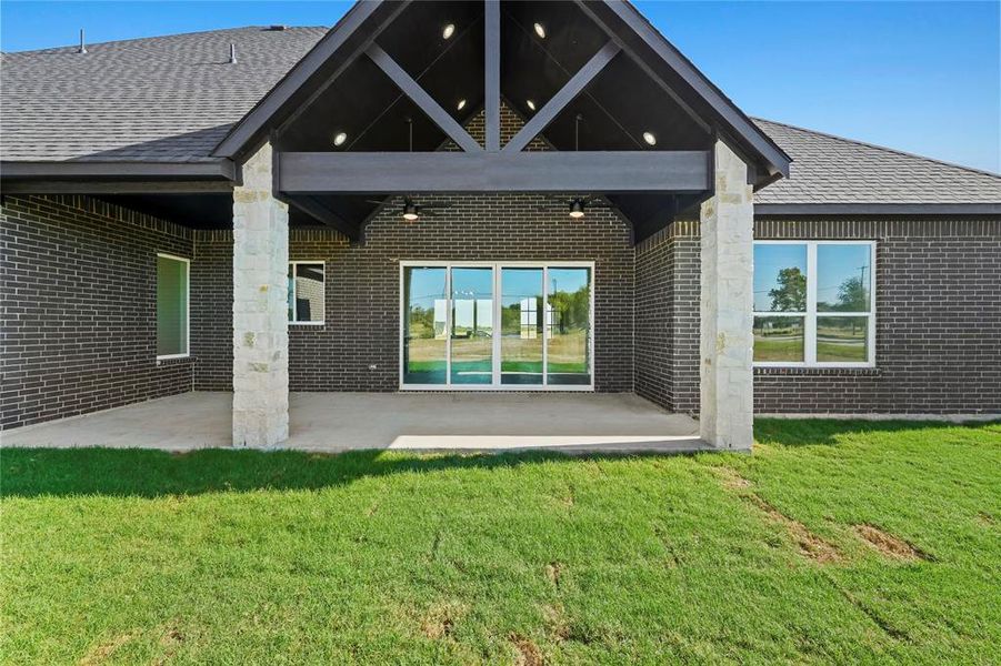 Rear view of property with brick siding, a patio, a lawn, and roof with shingles Rear view of property with brick siding, a patio, a lawn, and roof with shingles