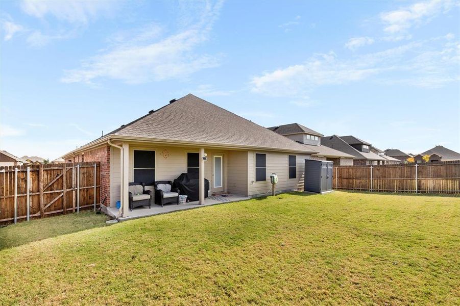 Rear view of property with a shingled roof, a patio, and a fenced backyard
