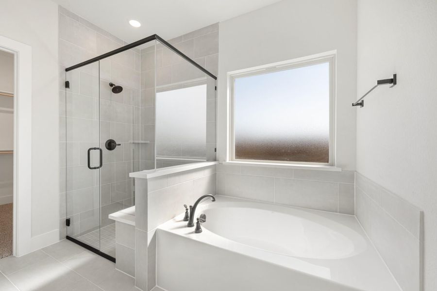 Bathroom with soaking tub, glass-enclosed walk-in shower, gray tile walls, and frosted window