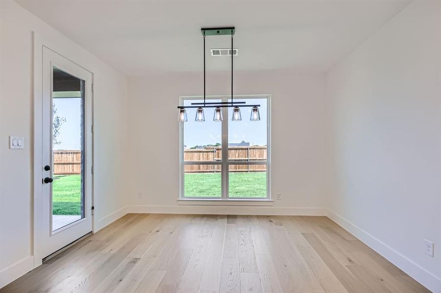 Unfurnished dining area with light wood-style floors and baseboards Unfurnished dining area with light wood-style floors and baseboards