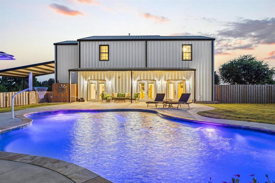 Pool at dusk with a patio area and french doors Pool at dusk with a patio area and french doors