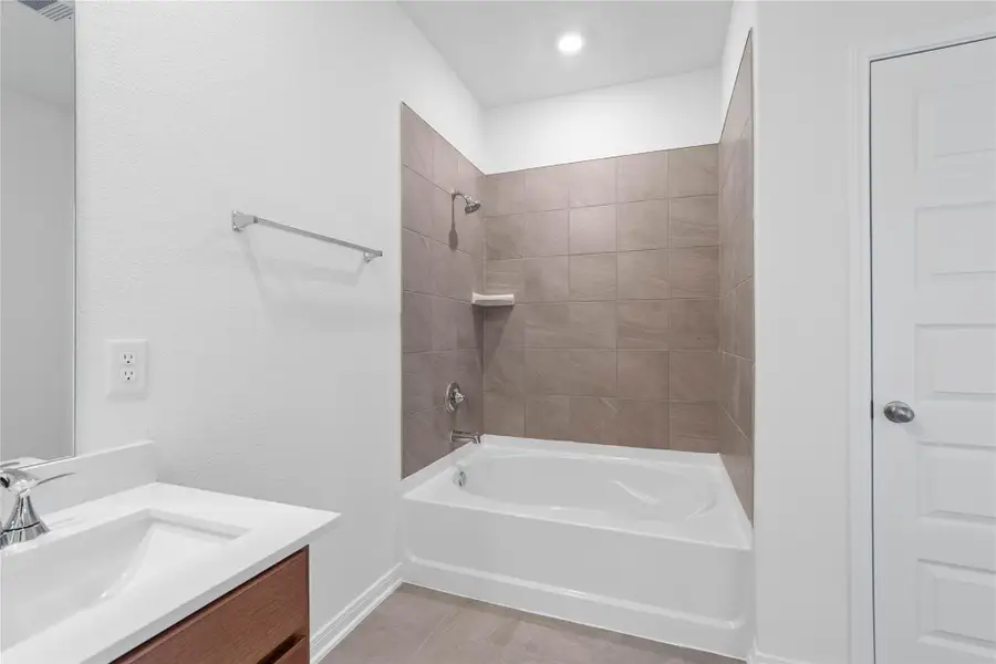 Additional view of the primary bathroom showcases the oversized tub/shower combination with tile surround and modern fixtures.