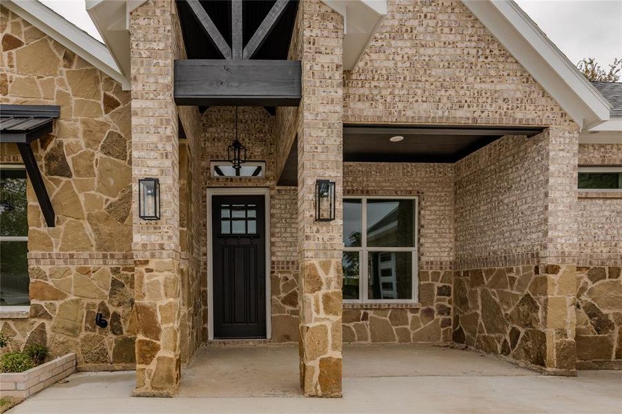 Entrance to property with stone siding and a patio area