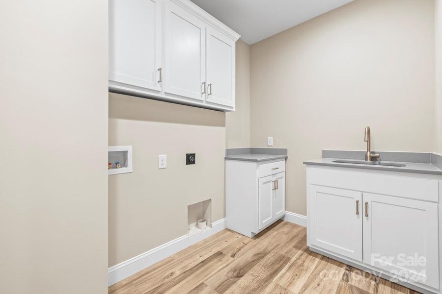 Large laundry room features a laundry sink, folding table and cabinets