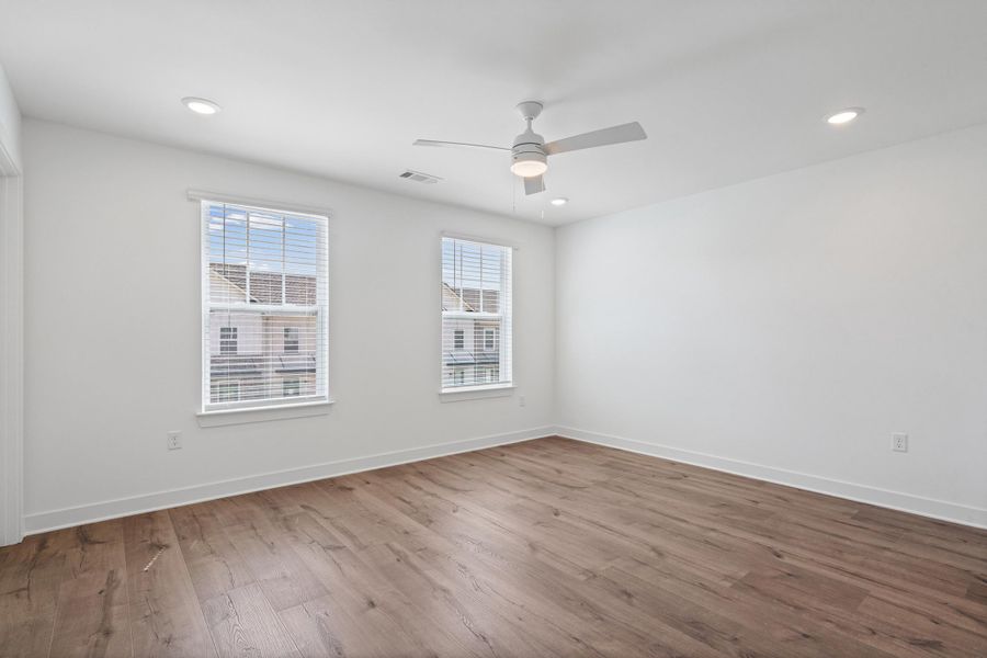 Spacious room featuring wood-finish flooring, recessed lighting, and a ceiling fan Spacious room featuring wood-finish flooring, recessed lighting, and a ceiling fan