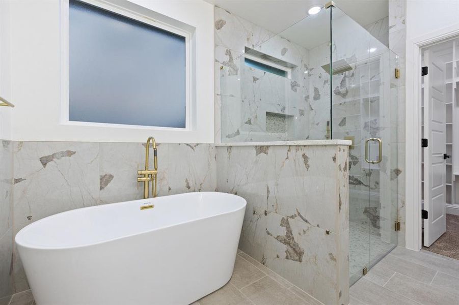 Full bathroom with tile walls, a marble finish shower, and a soaking tub