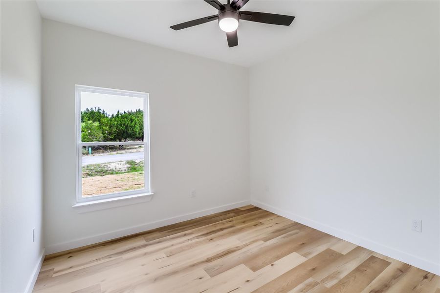 Spare room with baseboards, light wood-style floors, and ceiling fan