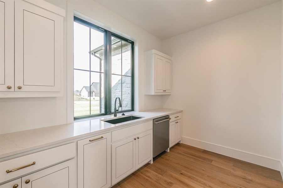 Kitchen with white cabinetry, light wood finished floors, stainless steel dishwasher, light stone counters, and recessed lighting
