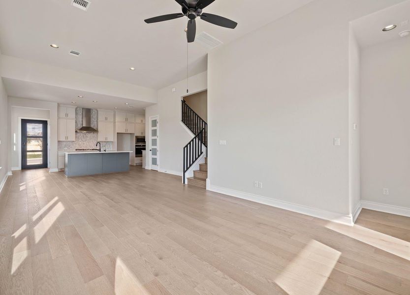 Unfurnished living room with baseboards, a ceiling fan, stairway, and light wood-type flooring Unfurnished living room with baseboards, a ceiling fan, stairway, and light wood-type flooring