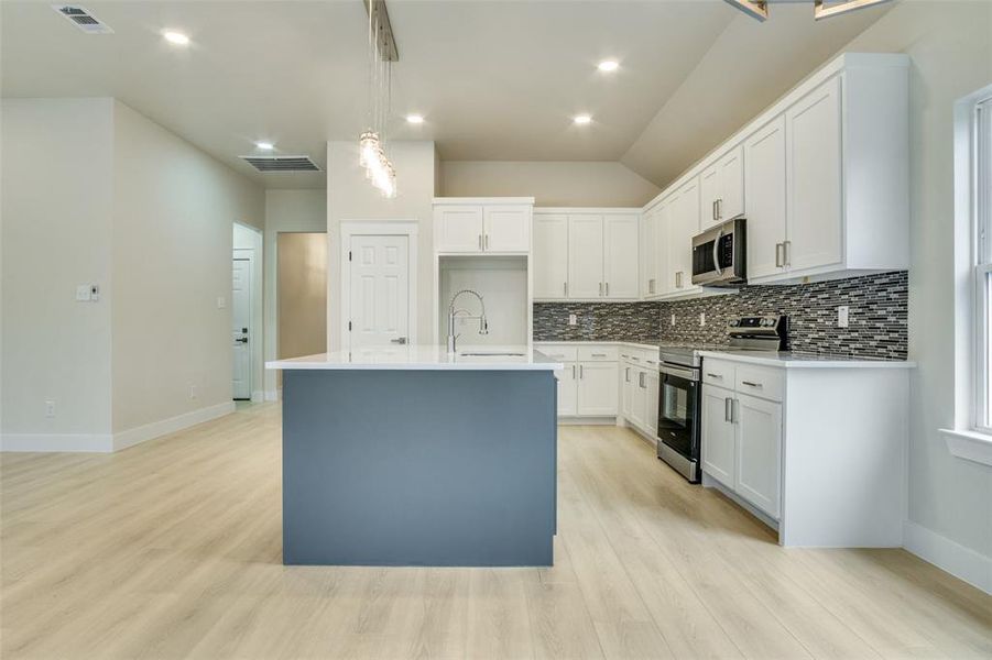 Kitchen with stainless steel appliances, visible vents, a sink, and tasteful backsplash