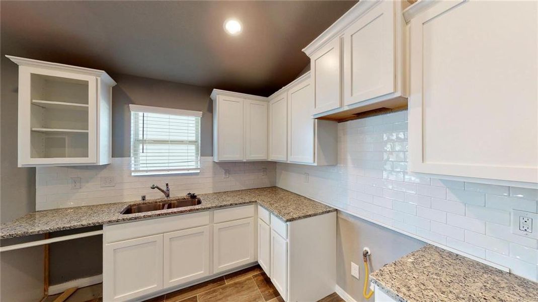 The close-up of the kitchen showcases the modern white cabinetry, granite countertops, and a double sink. The well-organized cabinets provide ample storage space, while the sleek design adds a contemporary touch to the heart of the home. This is a picture of an Elise Floor Plan with another Saratoga Homes.