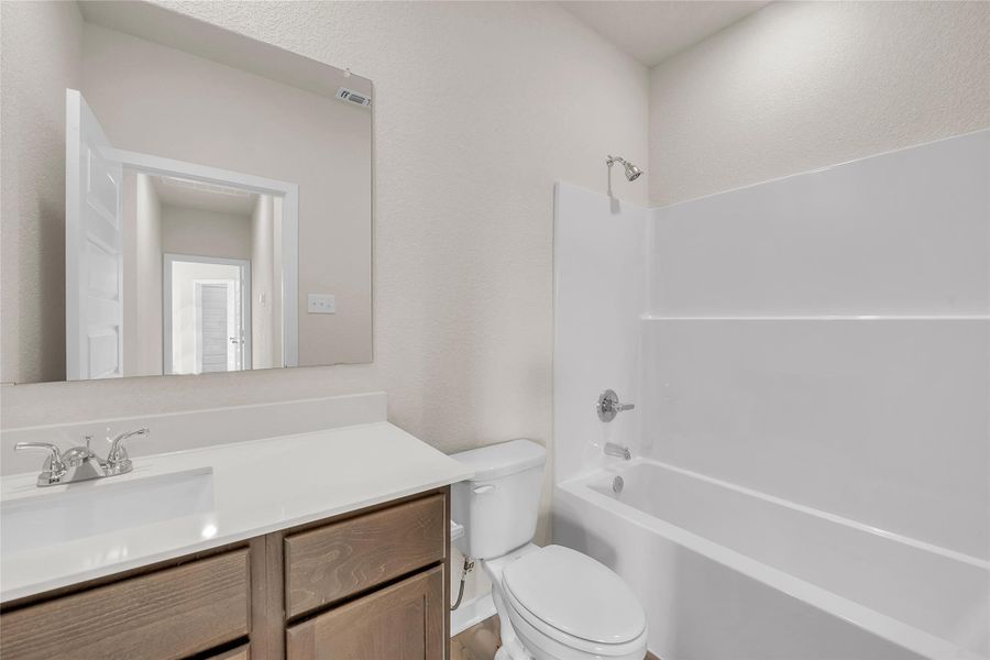 Bathroom featuring bathing tub / shower combination, vanity, and a textured wall
