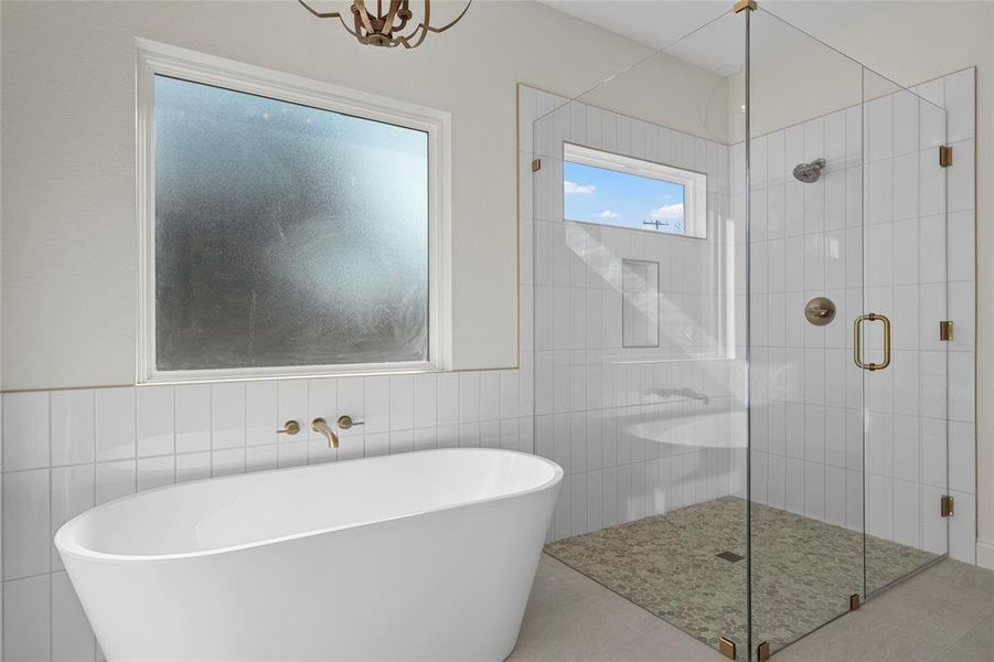 Bathroom with a freestanding bath, a stall shower, tile walls, and tile patterned floors Bathroom with a freestanding bath, a stall shower, tile walls, and tile patterned floors