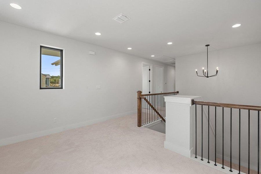 Hallway with an upstairs landing, light colored carpet, recessed lighting, and a chandelier