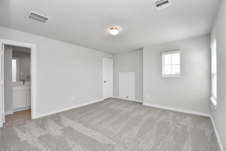 Secondary bedroom features plush carpeting, large windows that let in plenty of natural light, bright paint, and spacious closets.