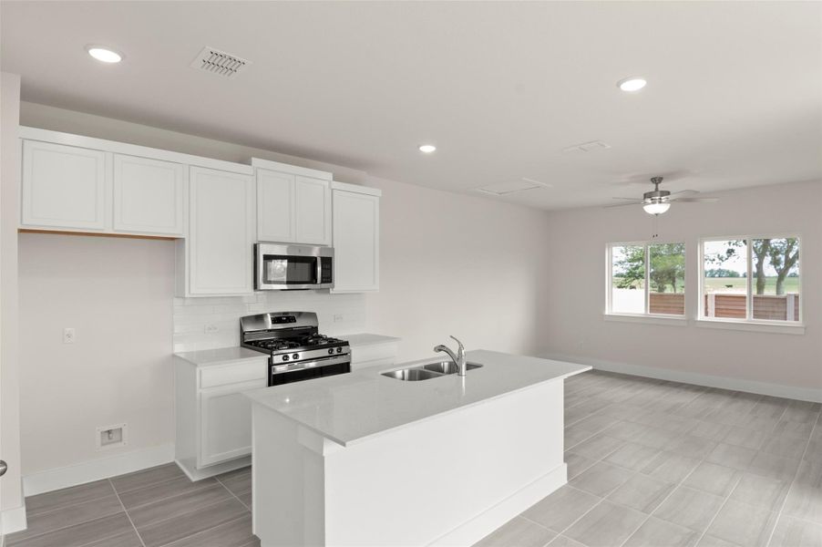 Kitchen with a sink, stainless steel appliances, baseboards, white cabinetry, and visible vents