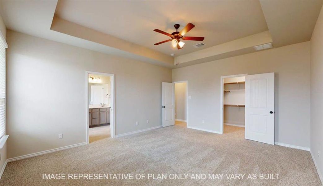 Unfurnished bedroom featuring a raised ceiling, light carpet, and a spacious closet Unfurnished bedroom featuring a raised ceiling, light carpet, and a spacious closet