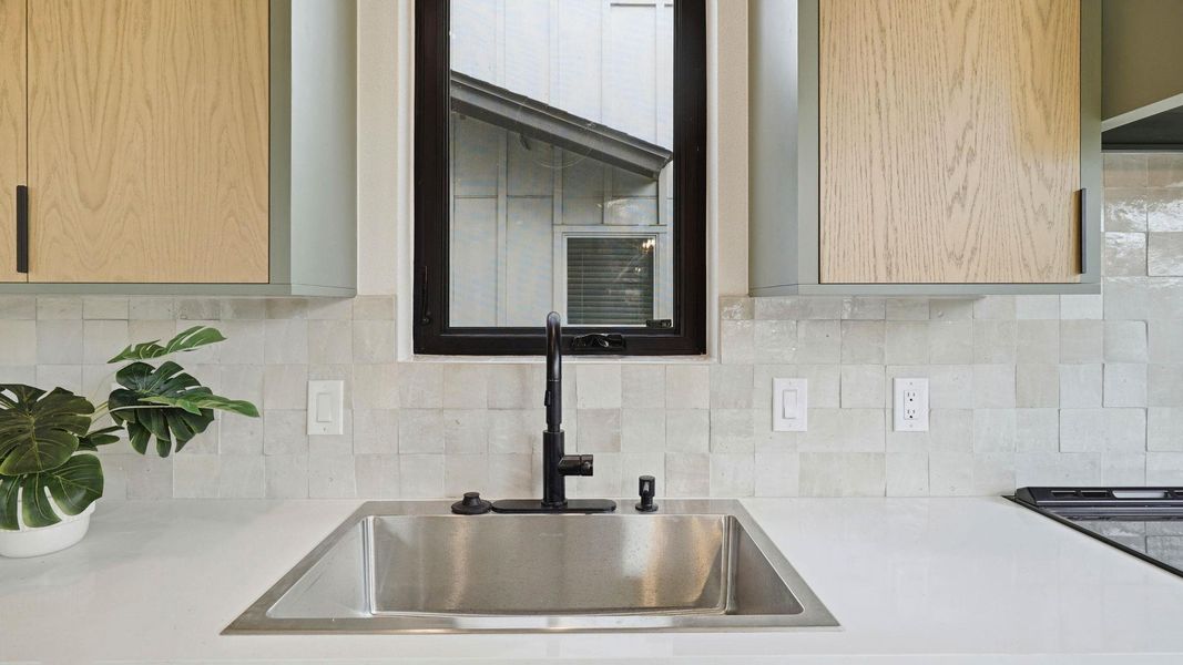 Kitchen view of light wood finish cabinets, extractor fan, and light stone countertops