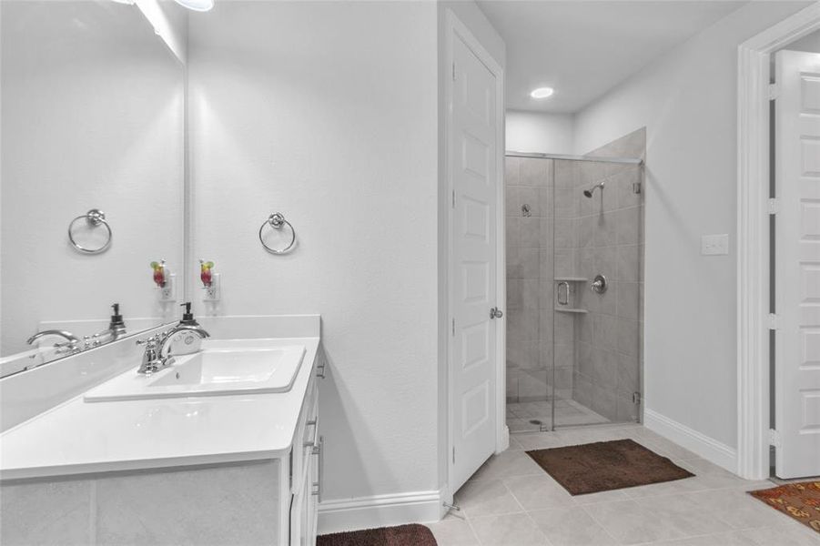 Bathroom with a stall shower, vanity, baseboards, and tile patterned floors