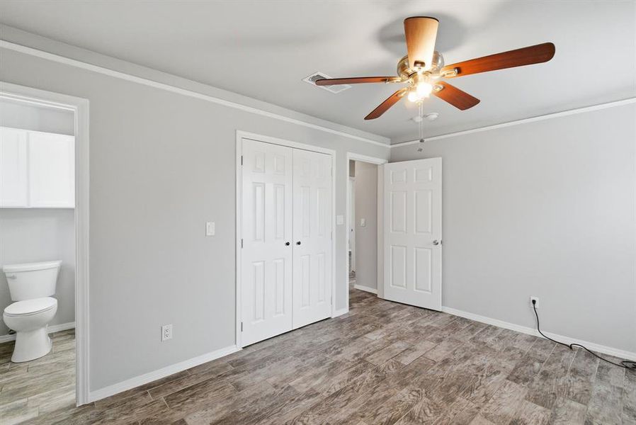 Unfurnished bedroom with crown molding, connected bathroom, light wood finished floors, ceiling fan, and a closet Unfurnished bedroom with crown molding, connected bathroom, light wood finished floors, ceiling fan, and a closet