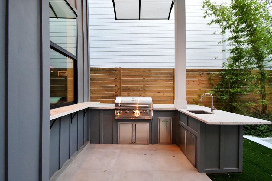 Outdoor kitchen with gas grill and sink.