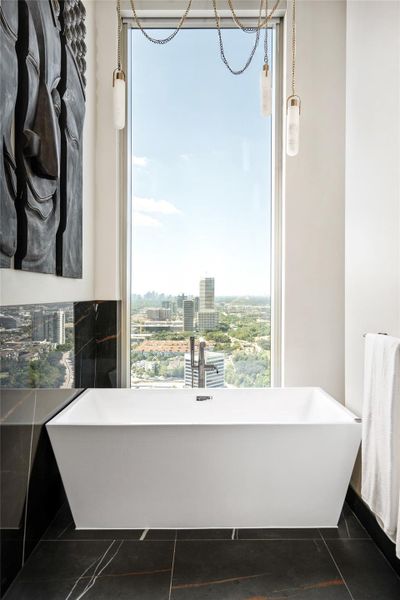 Soaking tub in the primary bathroom, framed by a floor-to-ceiling window with stunning views.