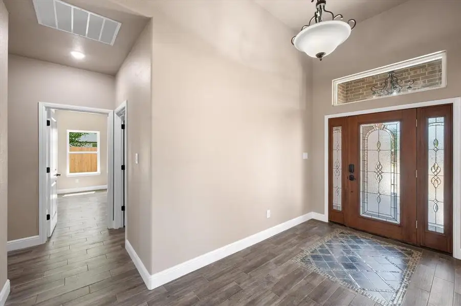 Wood-finish tile flooring in the entryway with an inset mosaic tile pattern