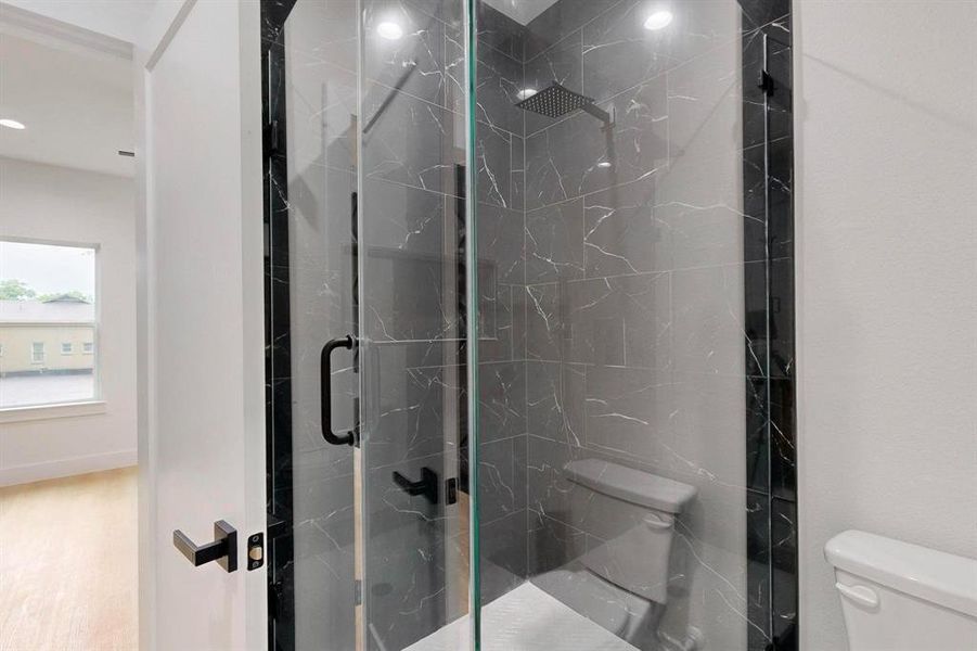 Full bath featuring toilet and a marble finish shower Full bath featuring toilet and a marble finish shower