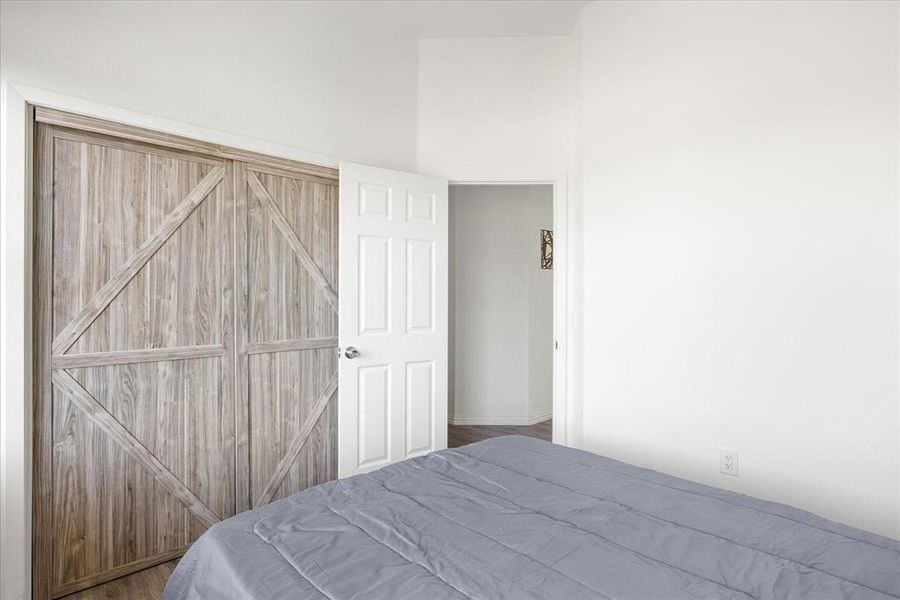 Bedroom with a barn door and hardwood / wood-style floors