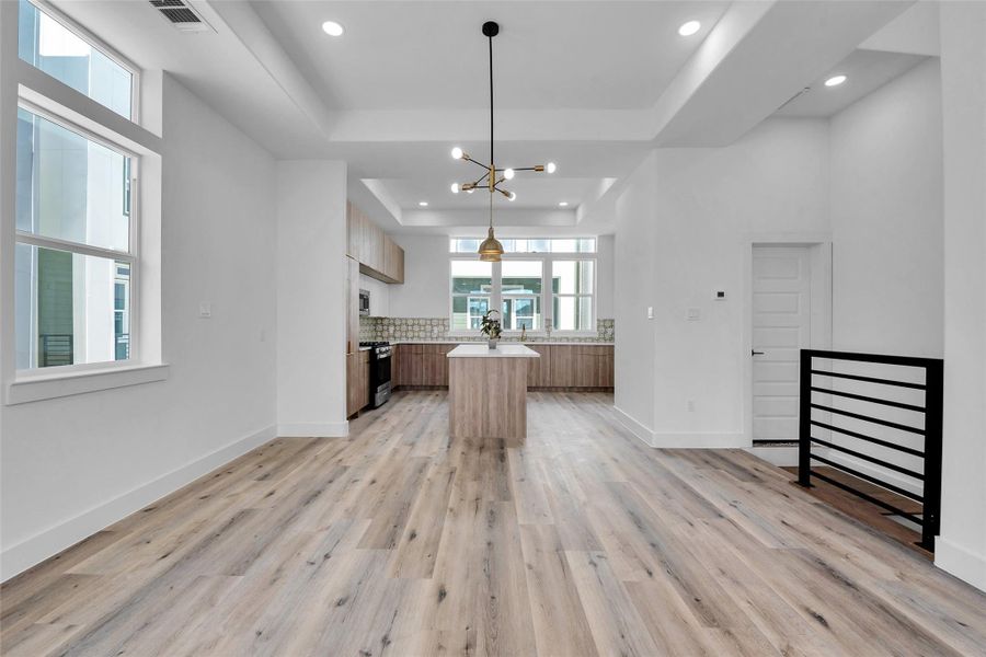 A view of the modern kitchen from the living room. The door to the right at the end of the stairs is the half bath. Expansive windows bring in lots of natural light into the kitchen and the living room.
