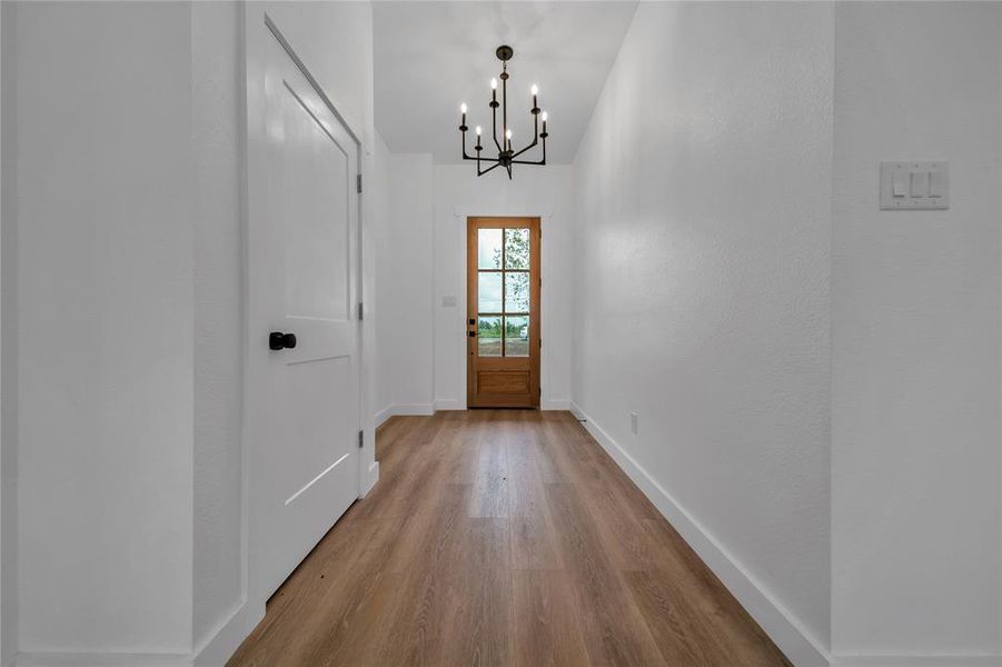 Doorway with light hardwood / wood-style floors and a notable chandelier