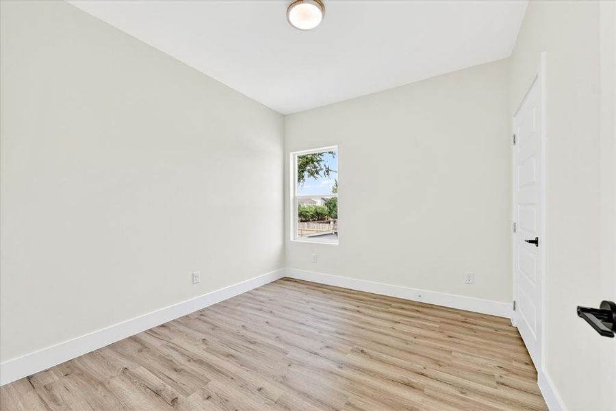 Room featuring wood-finish flooring, white baseboards, and neutral wall tones