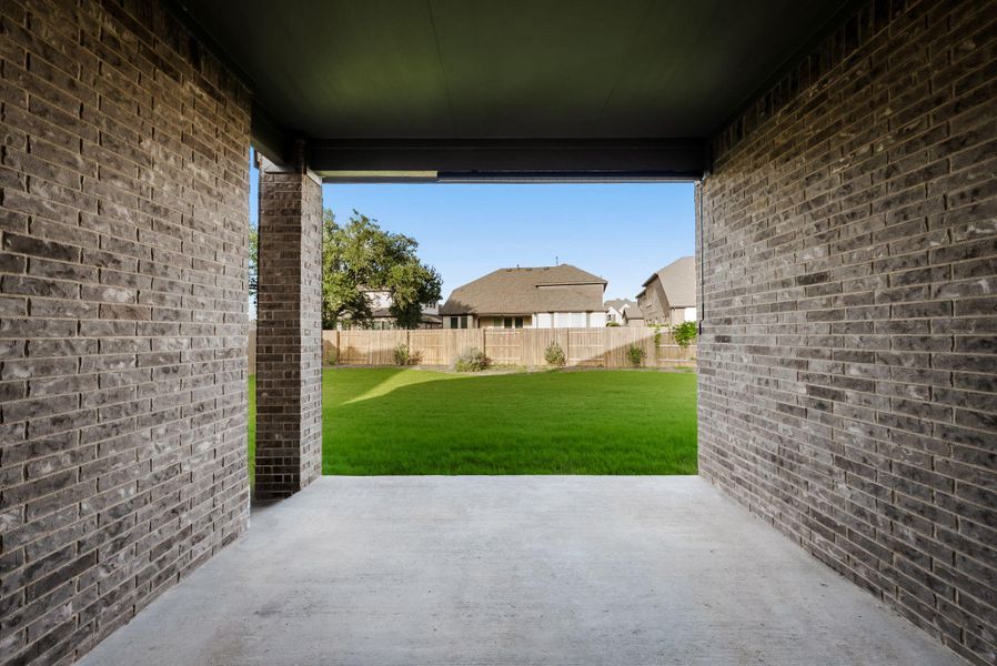 An inviting covered patio opens to a vibrant, green private yard, perfect for outdoor relaxation.