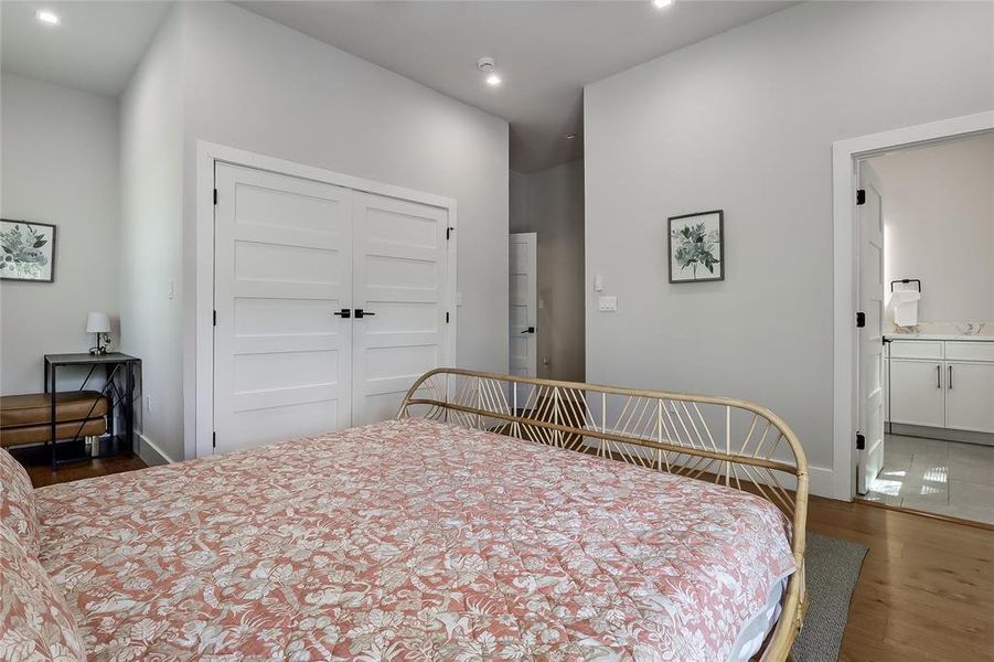 Hardwood flooring extends throughout this well-lit bedroom, offering ample storage behind clean, paneled doors.
