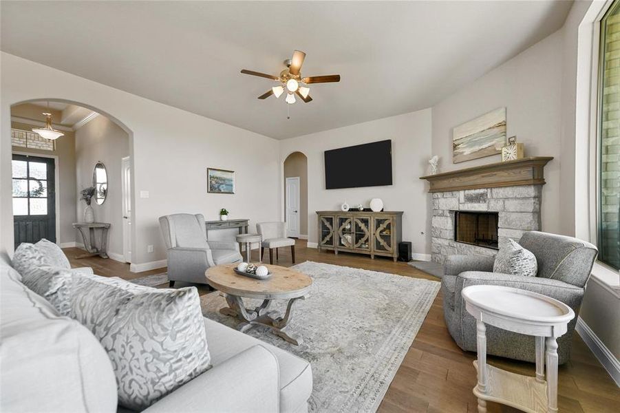 Living room featuring a fireplace, wood-type flooring, and ceiling fan