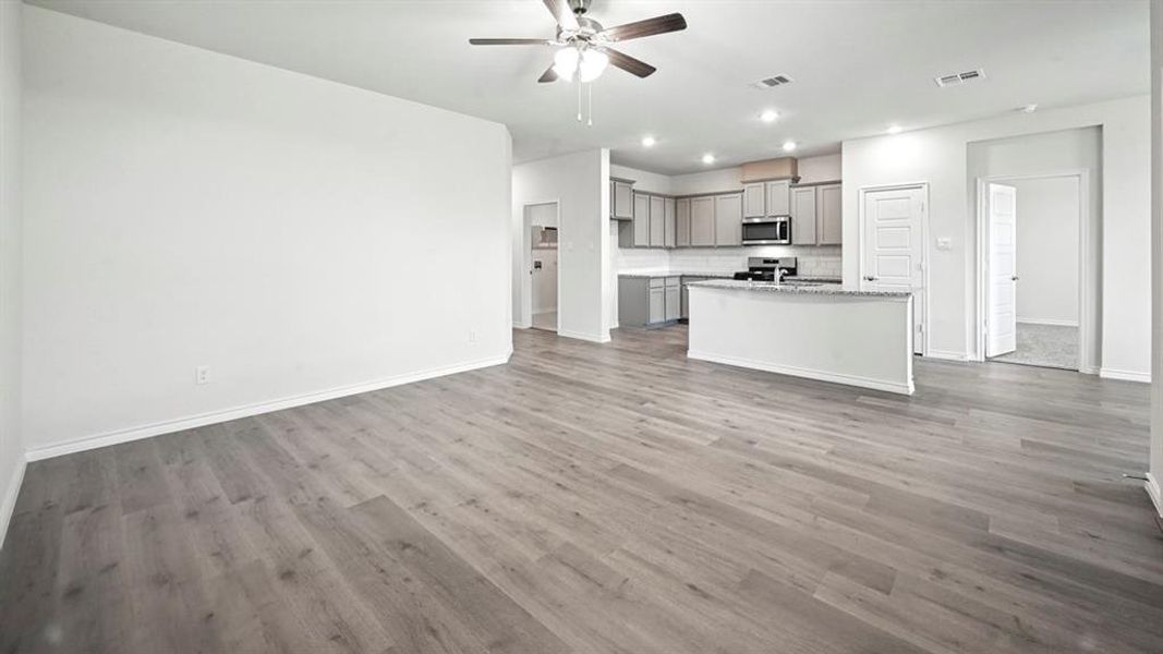 Bright open-concept living area featuring wood-finish flooring, recessed lighting, and a ceiling fan