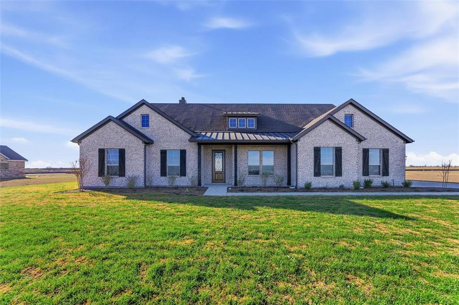 View of front of home featuring a standing seam roof, a metal roof, a front lawn, and a porch