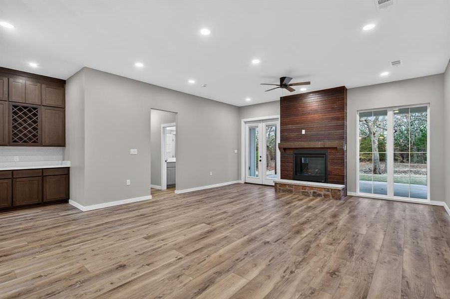 Living room fireplace includes antique headboard and stone from the property. Living area/family area faces the back yard with mature trees. Off to the side is a dry bar, great for entertaining!