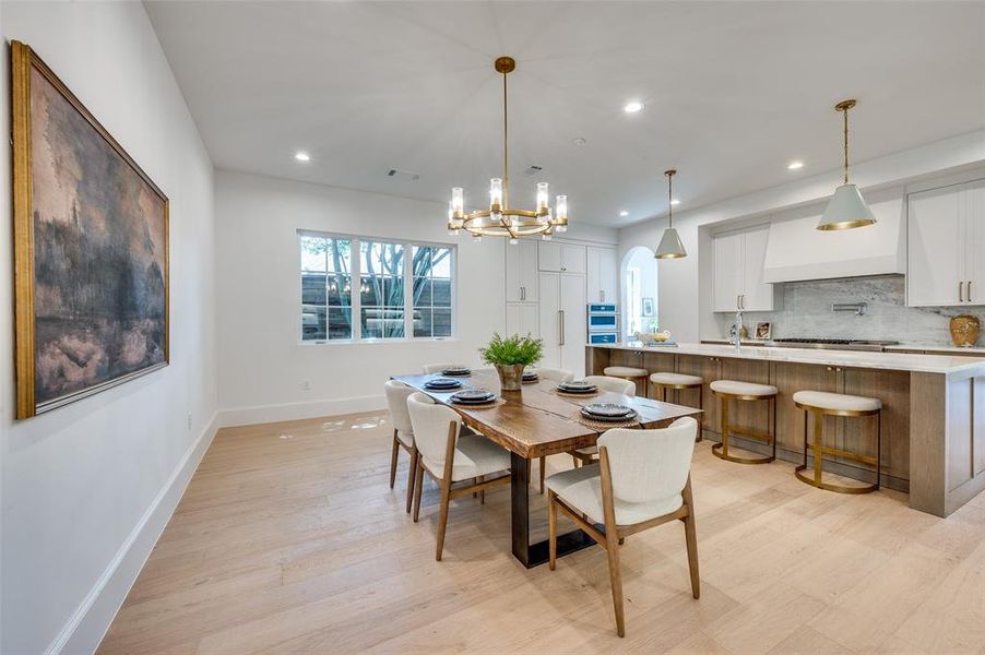 Dining space with recessed lighting, light wood-style floors, a chandelier, and arched walkways