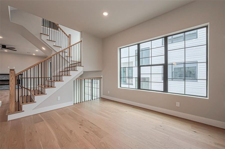 Explore this modern kitchen featuring sleek white cabinetry, stainless steel appliances, and a spacious central island. Enjoy hardwood floors, abundant natural light, and elegant pendant lighting.